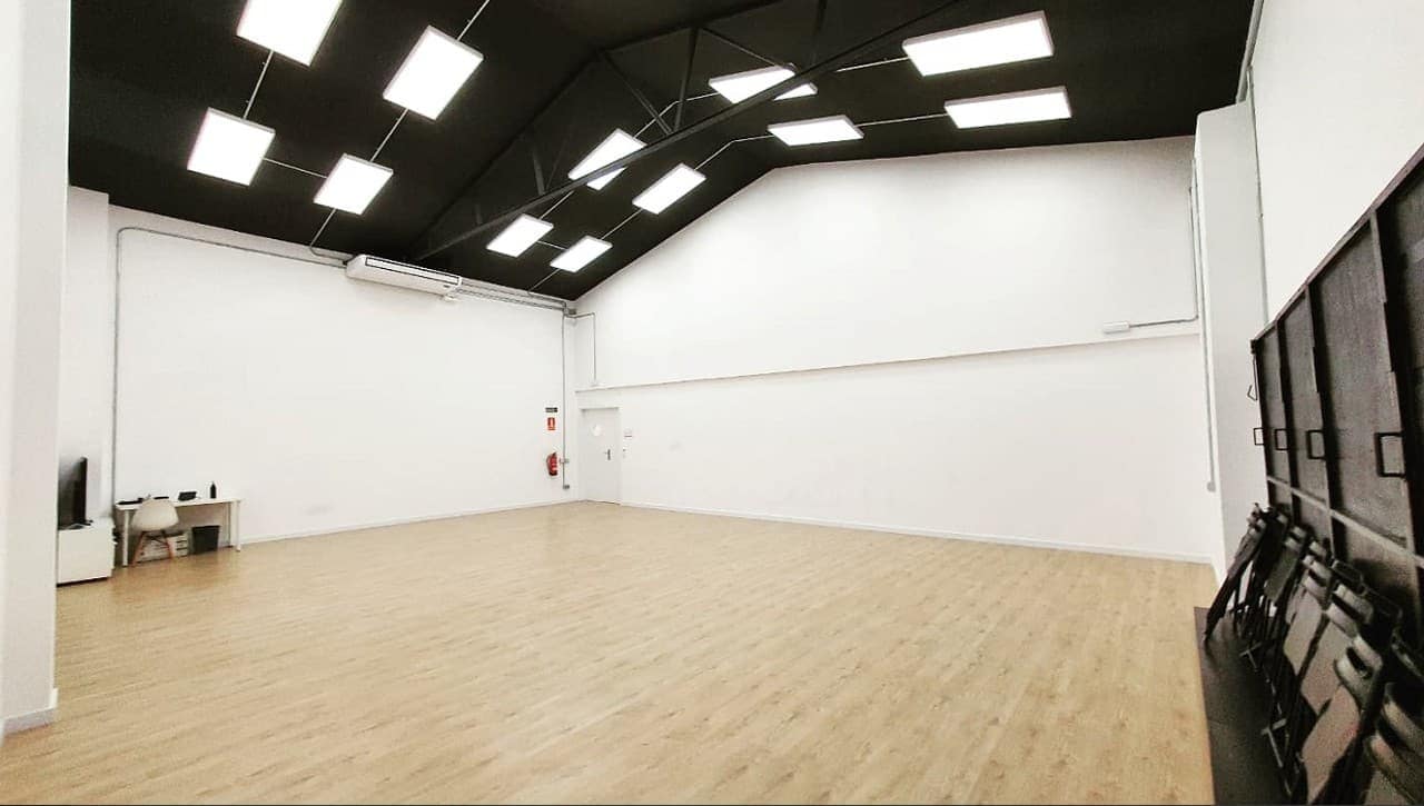 Sala de teatro con la cubierta vista pintada de negro, los focos suspendidos y las sillas apiladas al fondo