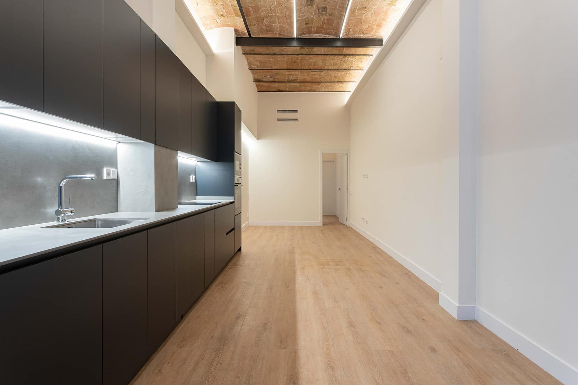 Cocina lineal en negro del piso de Ventura Plaja, bajo la bóveda catalana de ladrillo restaurada