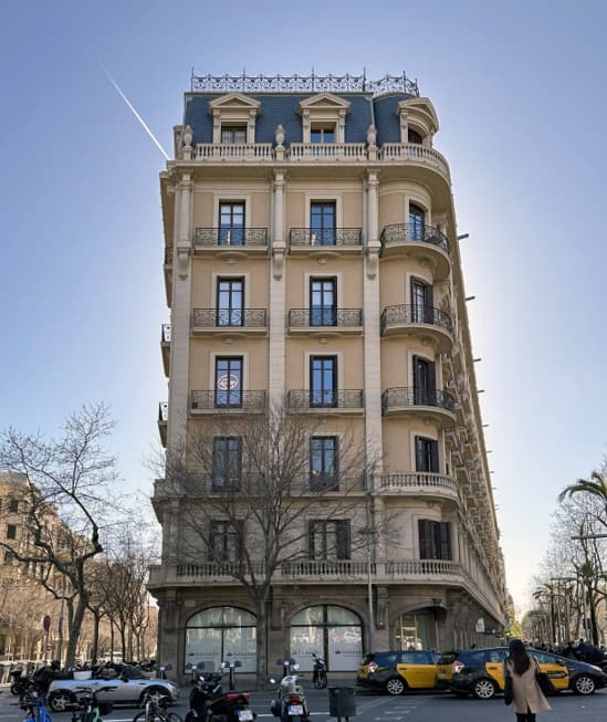 Fachada del edificio en chaflán, con los balcones de forja y la buhardilla de pizarra