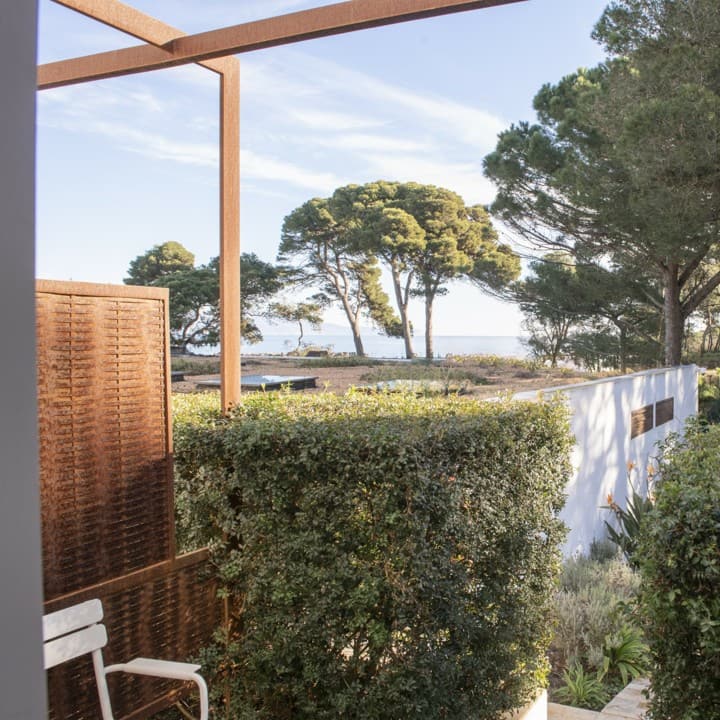 Vista al mar entre pinos desde una de las terrazas, con celosía de acero corten