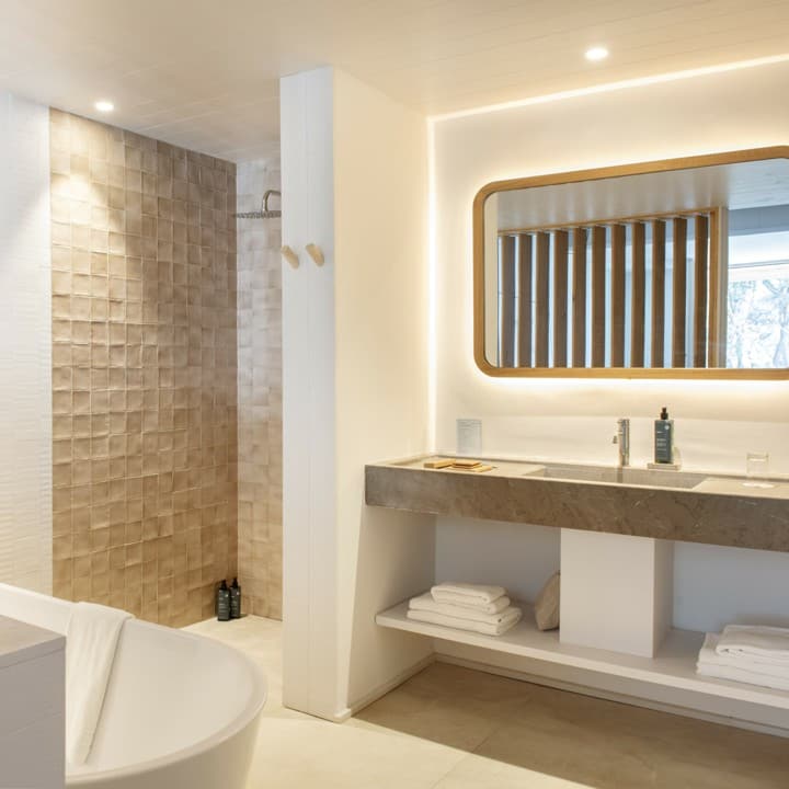Baño spa con ducha revestida de cerámica nacarada, bañera exenta y encimera de piedra