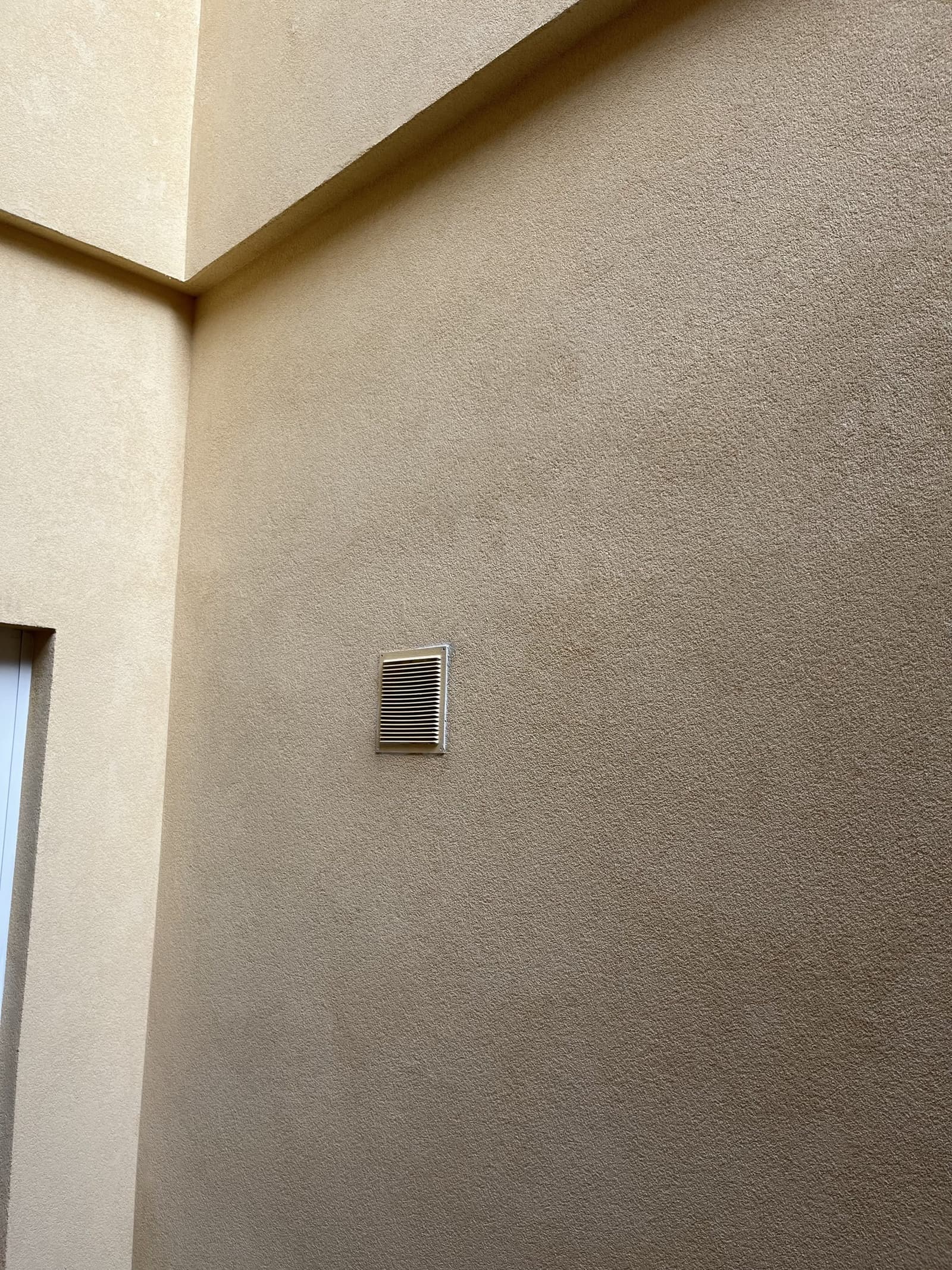 Detalle del revestimiento monocapa terminado, con una rejilla de ventilación integrada en el paño