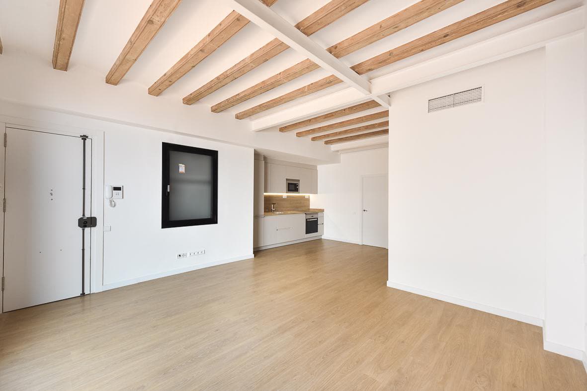 Salón con techo de vigas y la puerta de entrada de la vivienda