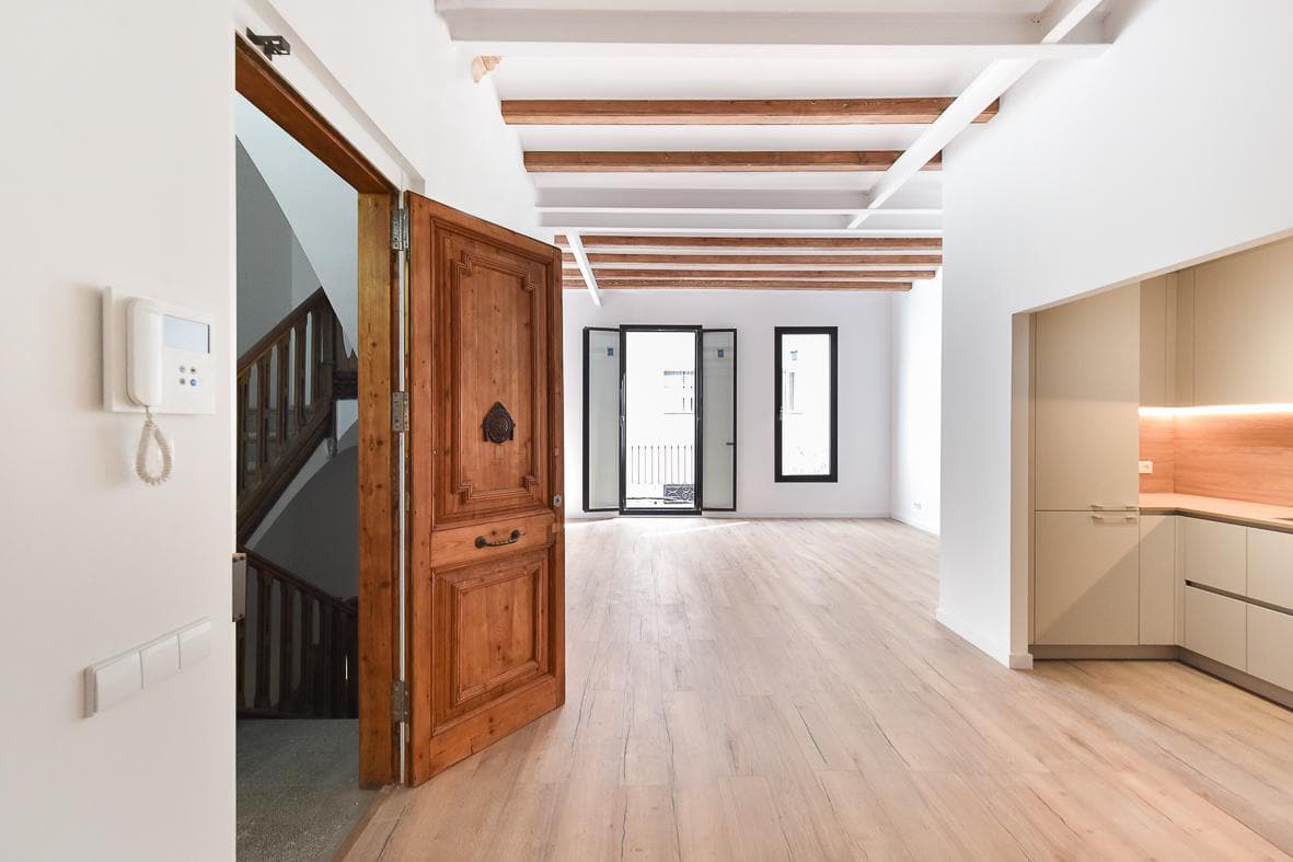 Recibidor con la puerta original de madera restaurada y la escalera comunitaria al fondo