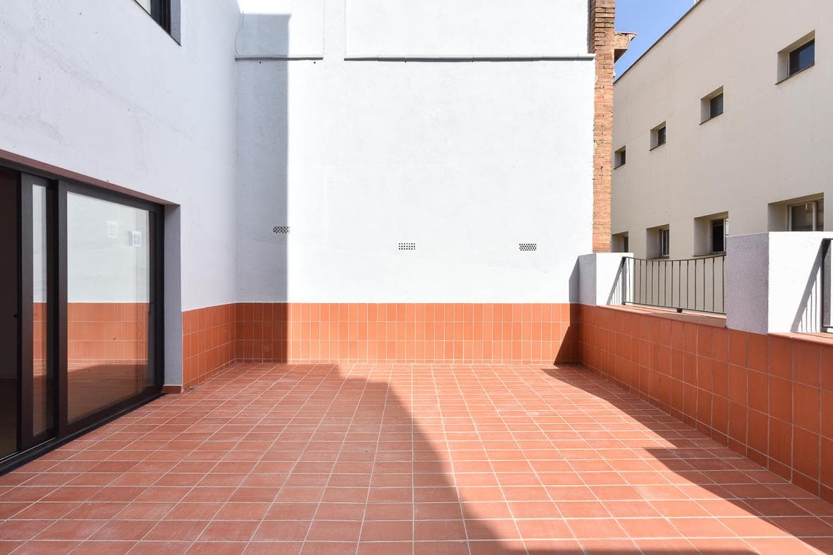 Terraza con pavimento y zócalo de gres rojo, entre las medianeras del patio de manzana