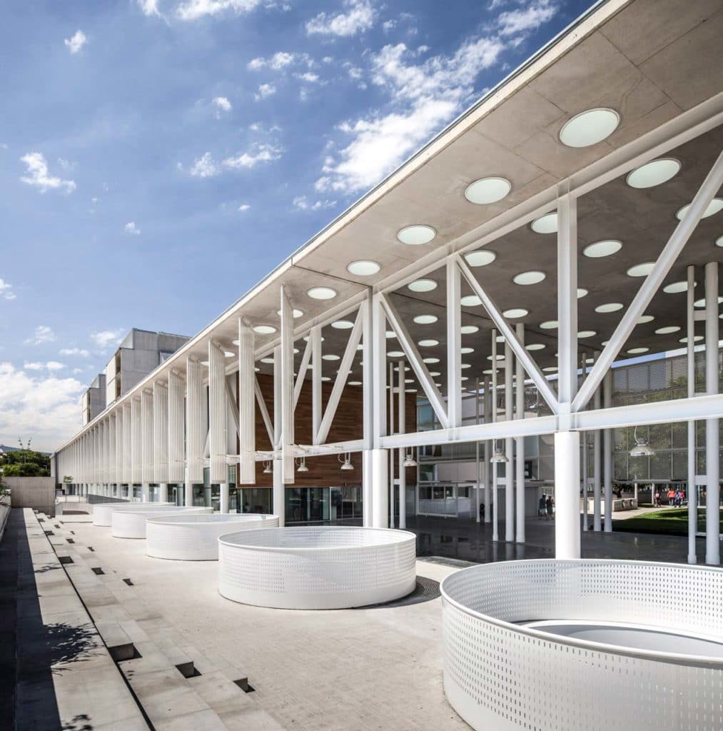 La estructura metálica del pórtico, en celosía blanca, con las jardineras cilíndricas perforadas en primer término
