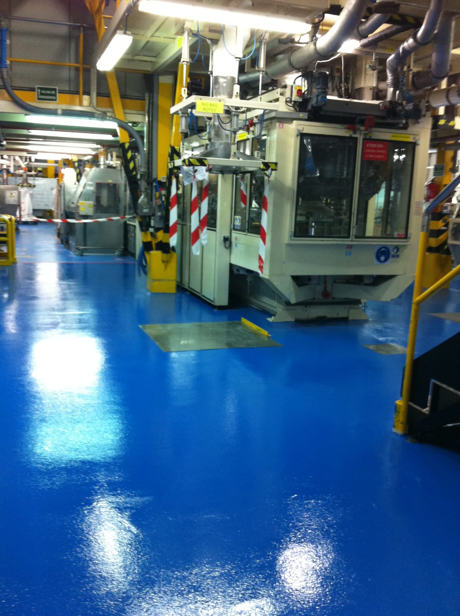 El pavimento multicapa azul recién aplicado, brillante, alrededor de una de las líneas de producción