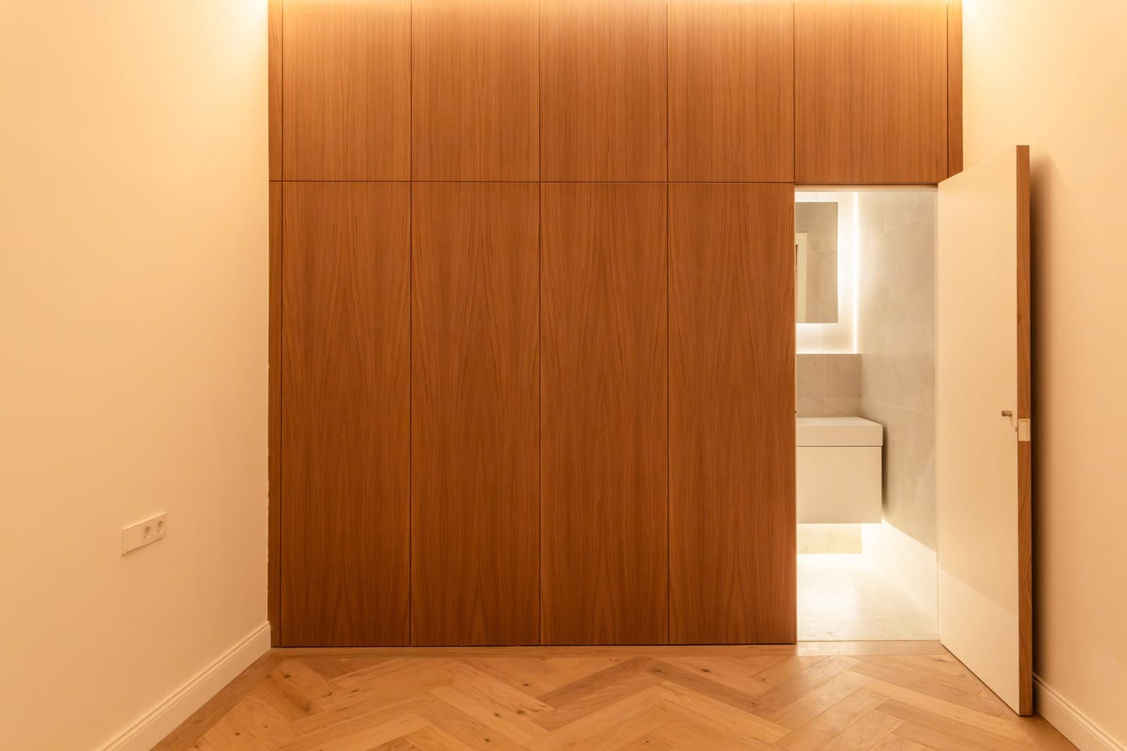 Dormitorio con frente de armario de roble a suelo y acceso al baño en suite