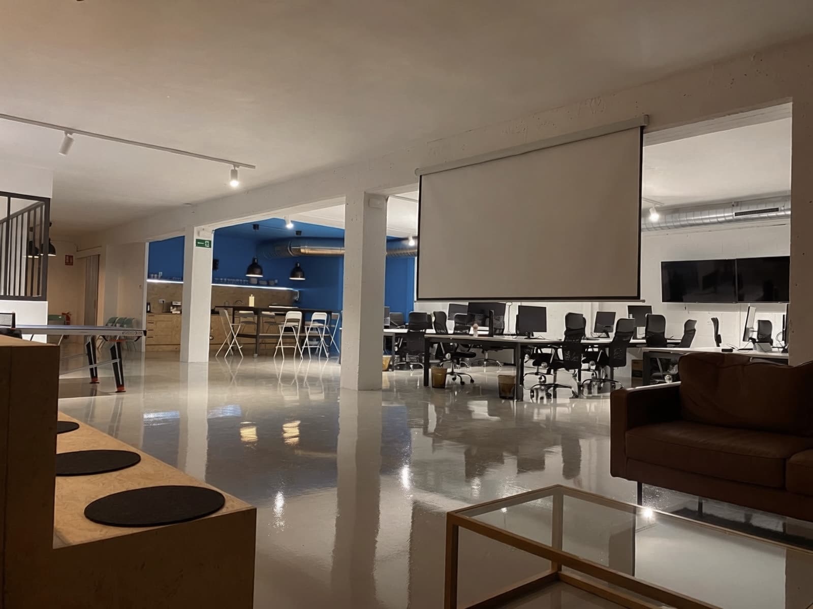 El espacio común con la pantalla de proyección desplegada y los puestos de trabajo al fondo