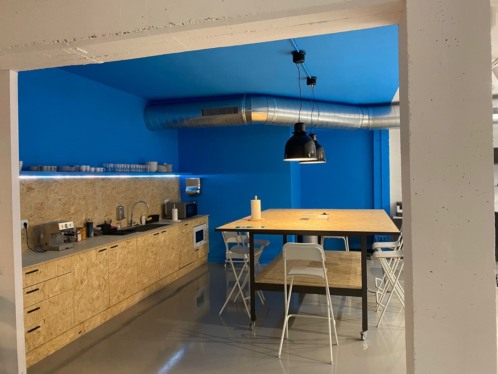 El office pintado de azul, con el mobiliario de tablero OSB, la tira LED bajo la balda y la mesa alta con ruedas
