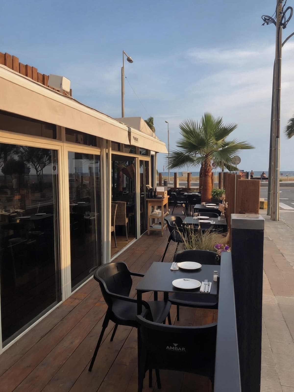La terraza cubierta junto al ventanal, con las mesas puestas y el mar al fondo