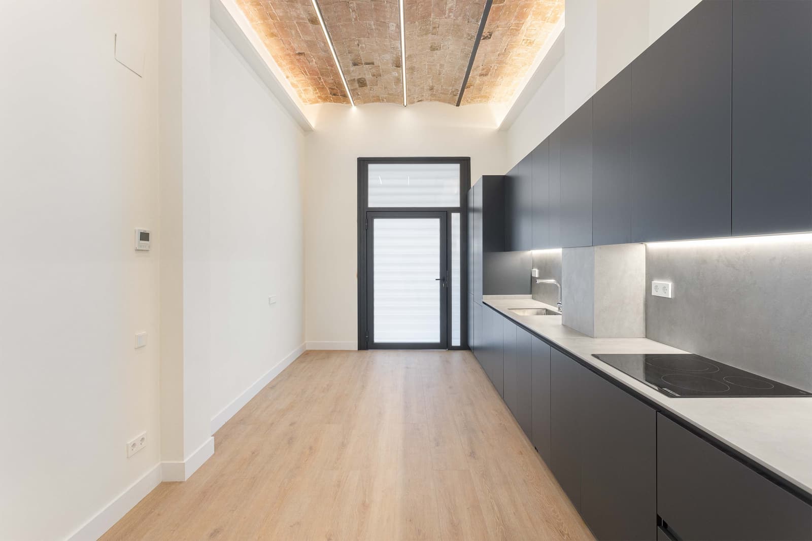 Cocina bajo la bóveda catalana restaurada, con iluminación lineal y salida al patio