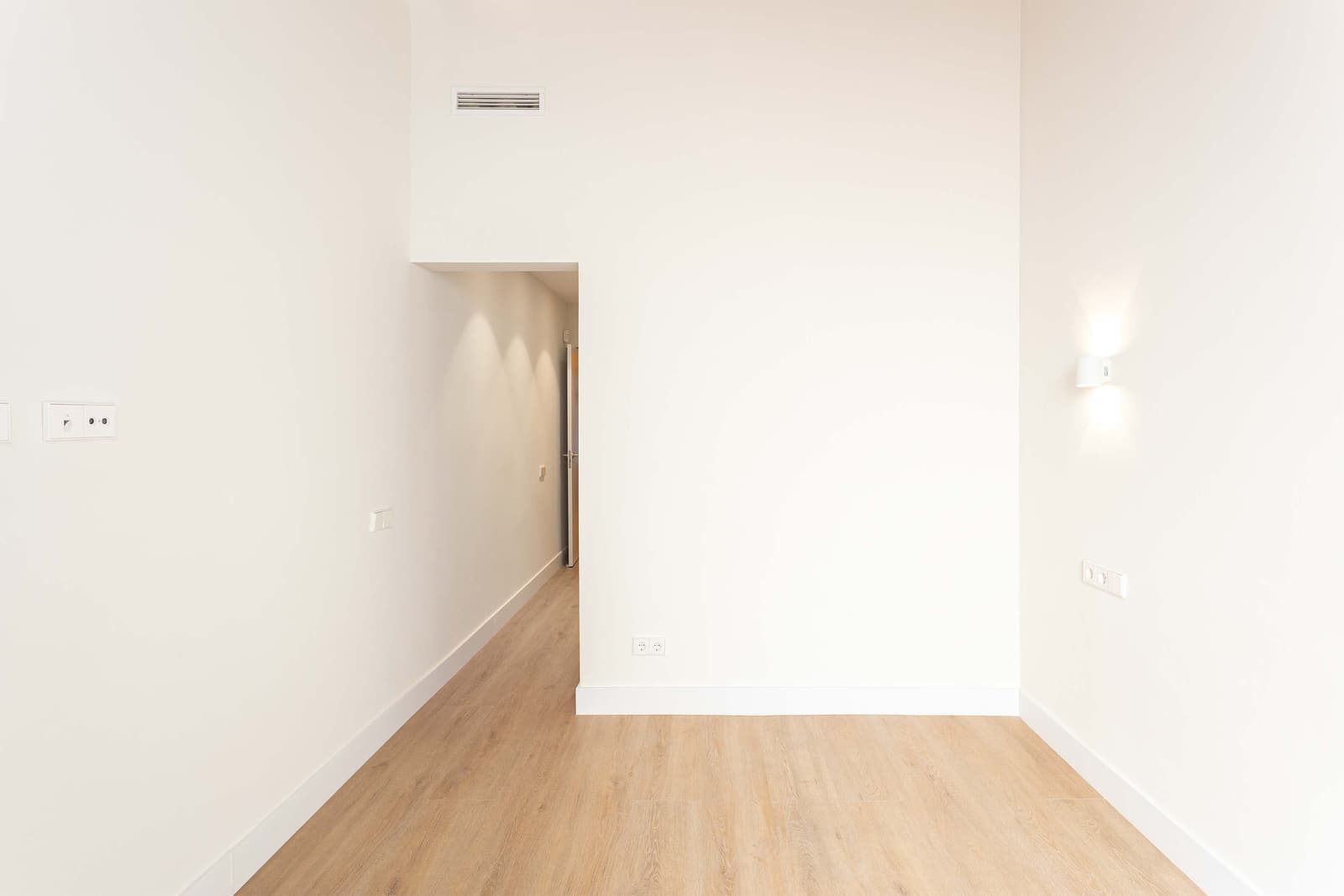 Habitación con suelo de madera laminada y aplique de pared