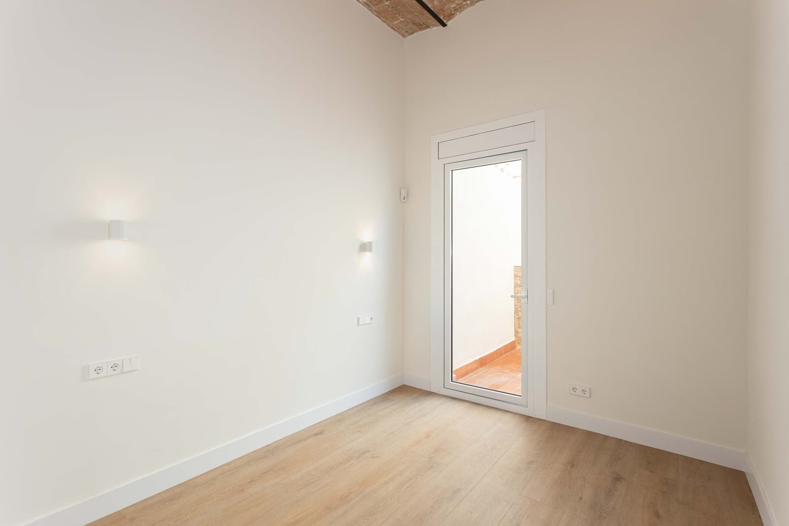 Habitación con salida al patio por una puerta de aluminio, bajo la bóveda de ladrillo