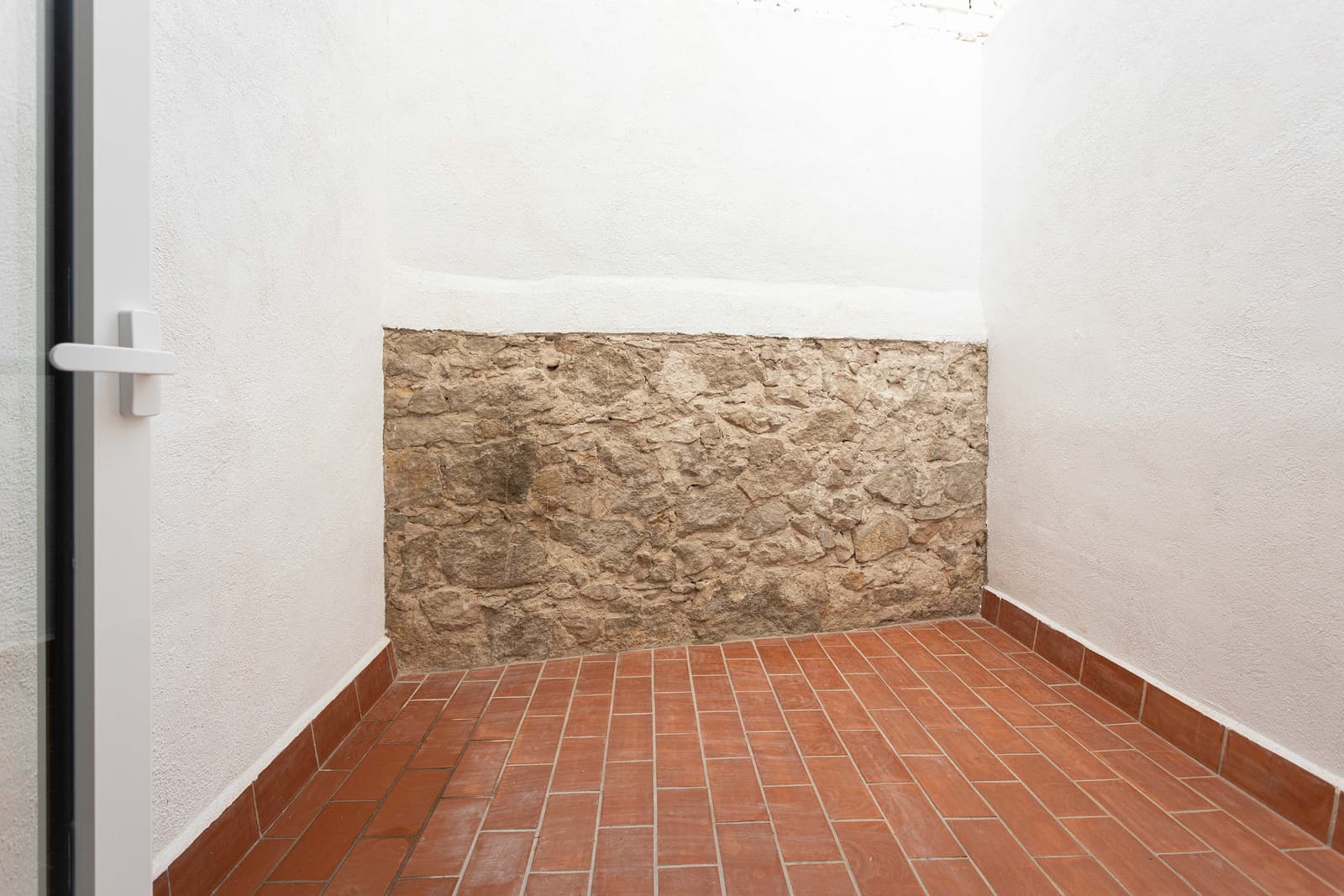 Patio con muro de piedra vista y pavimento cerámico de barro cocido