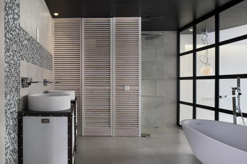 Baño principal con dos lavabos de piedra, ducha de obra y bañera exenta tras una vidriera negra