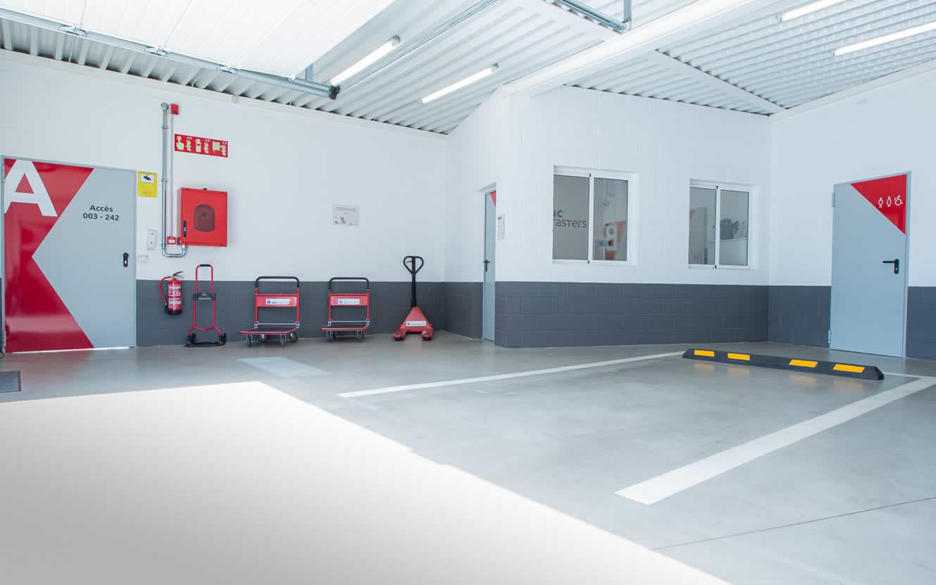 La zona de carga interior, con las puertas rotuladas, las carretillas y la señalización vial pintada en el pavimento