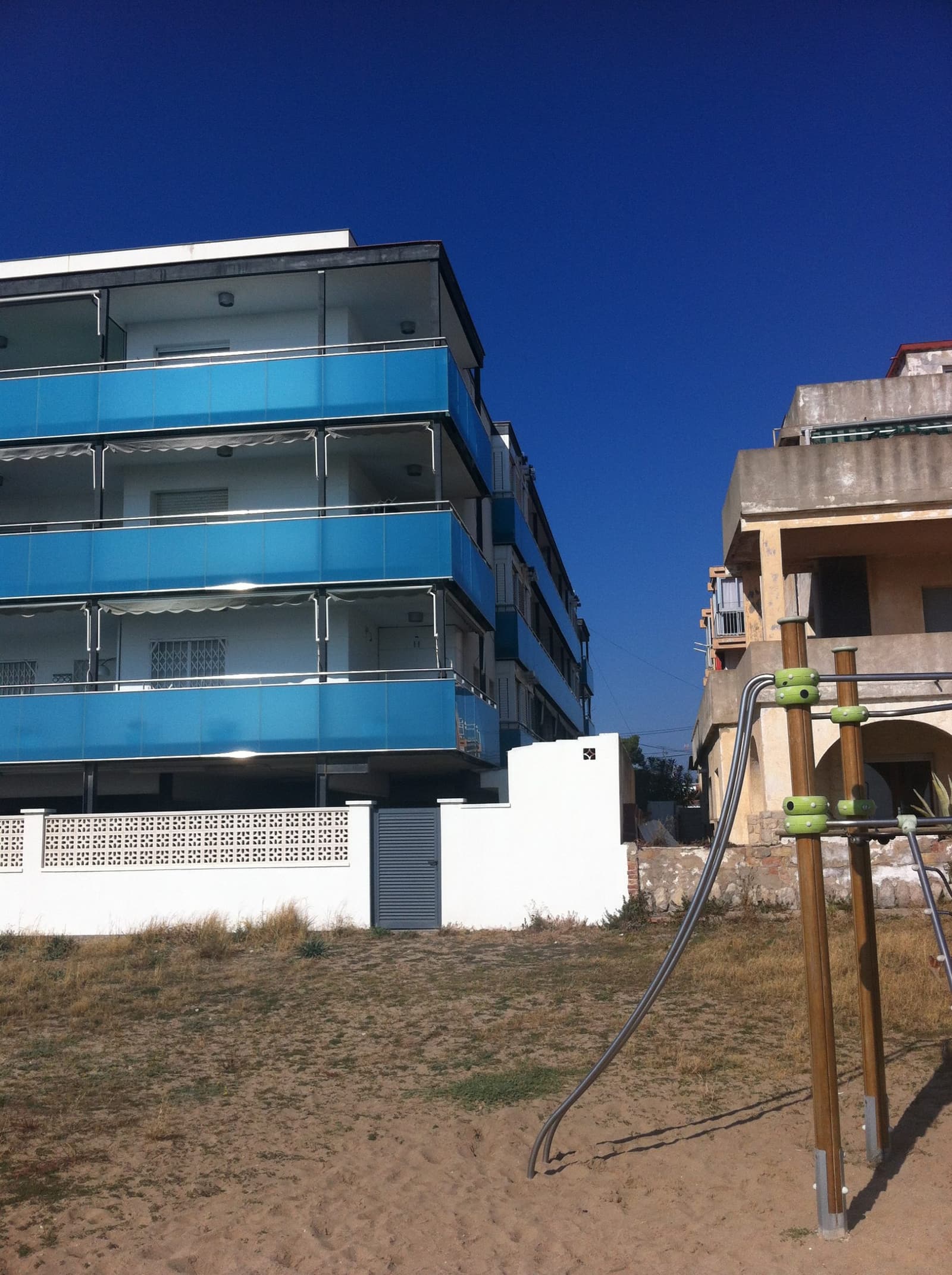 Los balcones desde el parque contiguo, con los frentes de vidrio y las barandillas metálicas a contraluz