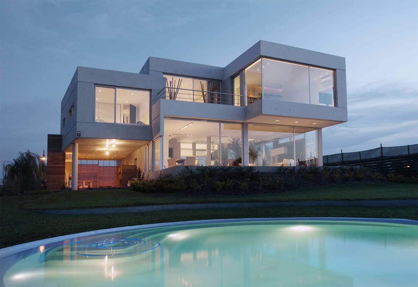 Vivienda unifamiliar moderna con piscina iluminada al atardecer